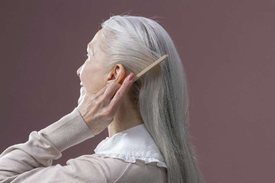 Adulta mayor peinando su cabello con canas