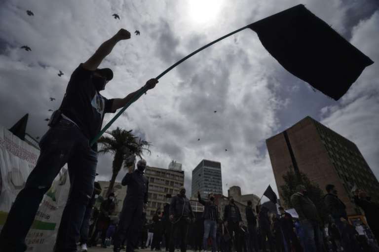Un hombre levanta los brazos con una bandera negra alzada por su mano izquierda.