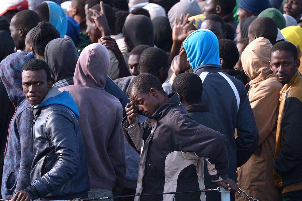 Un grupo de migrantes rescatados en el Mediterráneo espera desembarcar en el puerto de Sicilia, Italia. /AFP