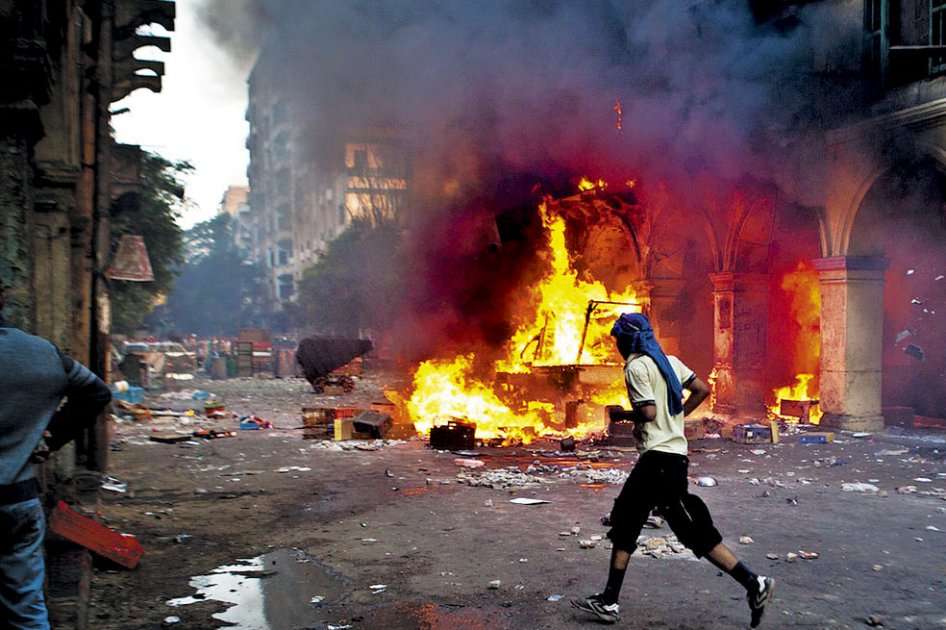 Un seguidor del presidente derrocado, Mohamed Mursi, pasa frente a un vehículo quemado en  la plaza Ramses en El Cairo, uno de los epicentros de las protestas y la represión del ejército. / AFP