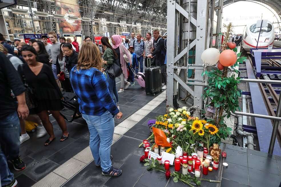 Ciudadanos dejan flores cerca al lugar donde un niño falleció tras ser empujado a las vías del tren por un hombre en la estación central de Fráncfort, Alemania. / EFE