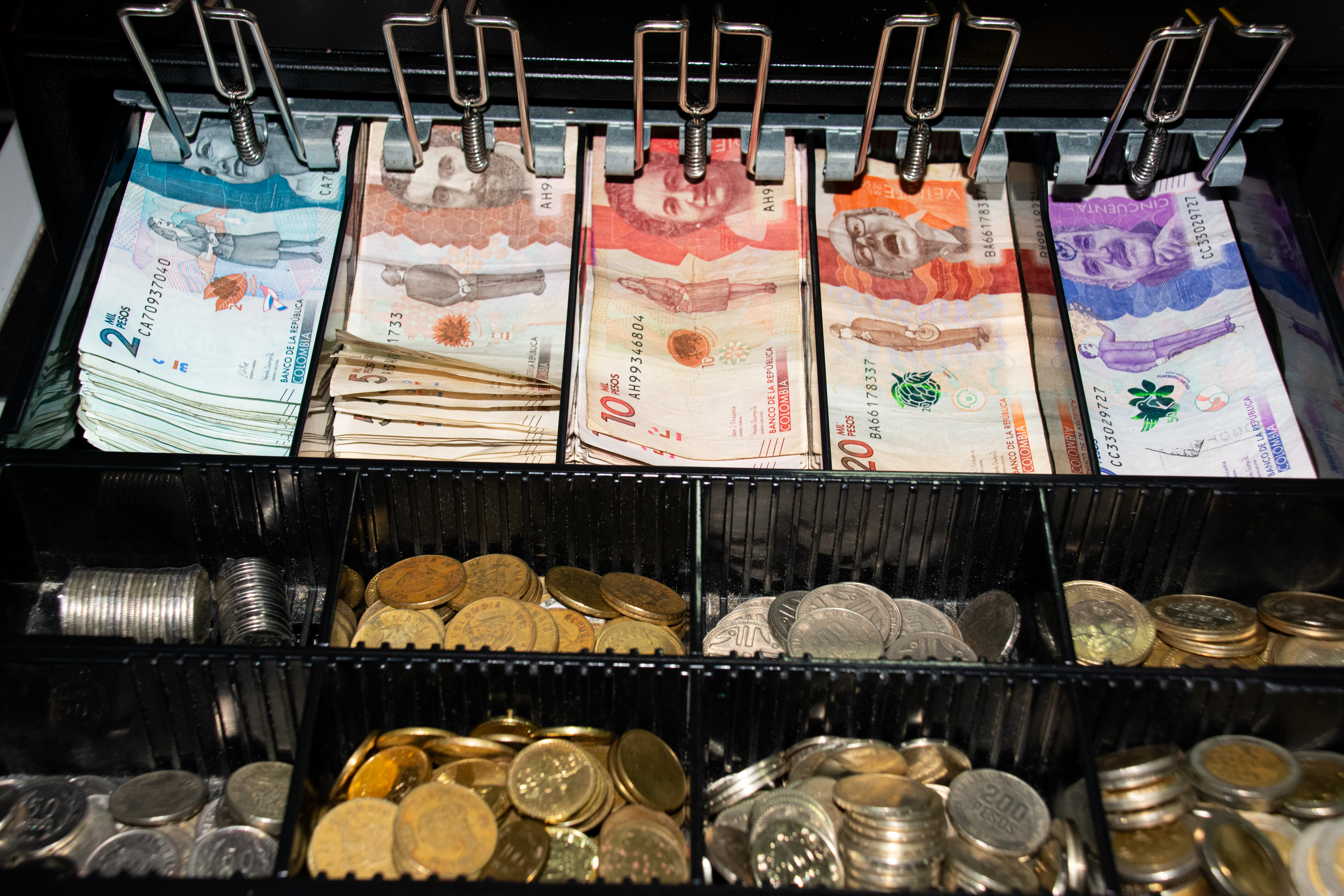 Caja registradora con billetes y monedas de Colombia.