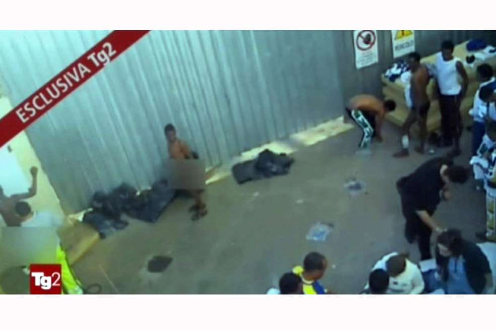 Imagen de una captura de televisión disponible el 18 de diciembre de un video emitido por la cadena pública italiana Rai2 el 16 de diciembre de 2013 en el que supuestamente se muestran varios inmigrantes siendo obligados a colocarse en fila desnudos a la intemperie para ser desinfectados, en Lampedusa, Italia. / EFE