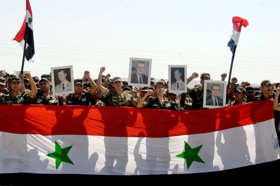 Soldados sirios con banderas de su país y retratos del presidente Bashar Al Assad durante una ceremonia para conmemorar el 67 Día del Ejército. Foto: EFE