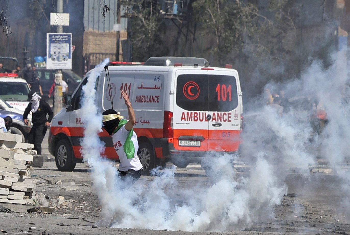 Un manifestante palestino usa una honda para devolver un bote de gas lacrimógeno hacia la seguridad israelí en medio de enfrentamientos durante una manifestación contra los asentamientos judíos y en apoyo de la mezquita Al-Aqsa de Jerusalén, en la calle principal de la aldea de Beita en la Cisjordania ocupada, el 15 de abril. 2022.