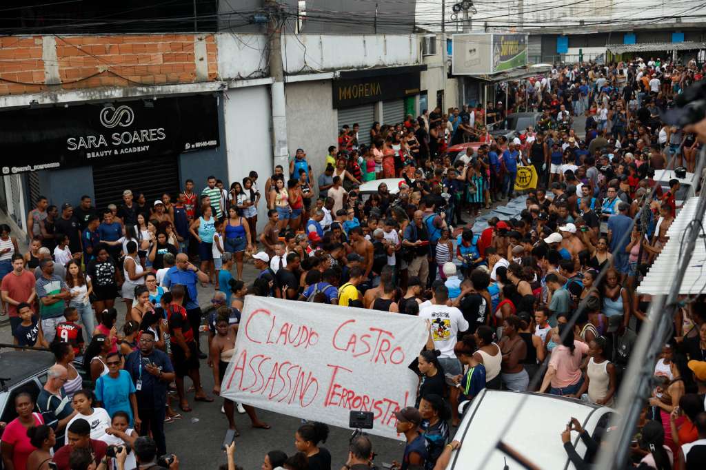 ATENCIÓN EDITORES: CONTENIDO GRÁFICO EXPLICITO AME3043. RÍO DE JANEIRO (BRASIL), 29/10/2025.- Personas sostienen un cartel contra el gobernador de Río de Janeiro, Claudio Castro, frente a cuerpos sin vida en una calle este miércoles, en Río de Janeiro (Brasil). Al menos 40 cuerpos sin vida fueron encontrados por los habitantes de las favelas de Río de Janeiro que ayer fueron escenario de una letal operación policial y fueron colocados por los vecinos en una plaza del barrio de Penha, según pudo confirmar EFE, que acompañó el rescate de algunos de los cadáveres. EFE/ Antonio Lacerda