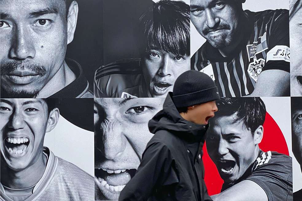 Joven delante de cartel publicitario en el centro de Tokio.
