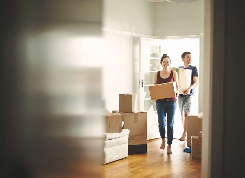 Shot of a young couple carrying boxes into their new place