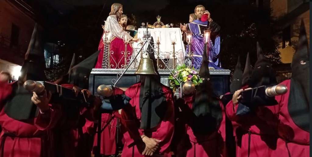 Cargueros de la Cofradía Pasionista de la Parroquia El Calvario, con túnicas rojas y capirotes negros en la procesión de prendimiento.