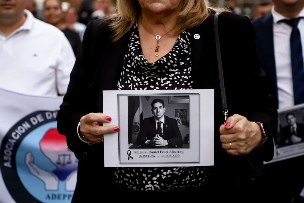 AME9237. ASUNCIÓN (PARAGUAY), 13/05/2022.- Una mujer sostiene una foto de Marcelo Pecci mientras marcha junto a cientos de personas que se suman este viernes a sendas marchas y un emotivo homenaje al fiscal antimafia Marcelo Pecci, asesinado en Colombia, en Asunción (Paraguay). Funcionarios judiciales encabezados por la fiscal general, Sandra Quiñónez, marcharon desde la sede del Ministerio Público hasta el Panteón de los Héroes, en el centro histórico de Asunción. Hasta ese lugar acudieron, además, manifestantes convocados por exalumnos del colegio San José, donde cursó sus estudios Pecci, quien a sus 45 años era uno de los fiscales más reputados del país. EFE/ Nathalia Aguilar