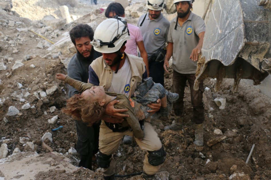 Un voluntario de los Cascos Blancos rescata a un niño de los escombros tras un bombardeo en Karm Homad, al norte de Alepo. / AFP