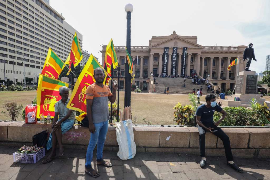 Colombo (Sri Lanka), 15/07/2022.- A man waves Sri Lanka's national flags outside the Presidential Secretariat following the resignation of Gotabaya Rajapaksa as president, in Colombo, Sri Lanka, 15 July 2022. The Parliament of Sri Lanka on 15 July accepted the resignation of Rajapaksa after he fled to Singapore through the Maldives following months of anti-government protests fueled by the ongoing economic crisis. Prime Minister Ranil Wickremesinghe was sworn in as interim president on 15 July. (Protestas, Maldivas, Singapur, Singapur) EFE/EPA/CHAMILA KARUNARATHNE