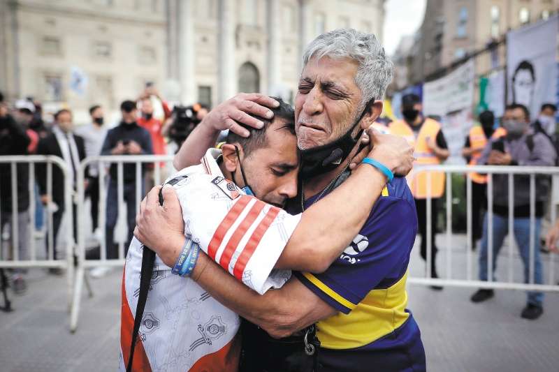 Un aficionado con la camiseta del Boca Juniors y otro con la camiseta del River Plate, se abrazan luego de despedir los restos de Diego Armando Maradona en el velatorio de la capital bonaerense, hoy jueves en la Plaza de Mayo.- EFE/Juan Ignacio Ronconori