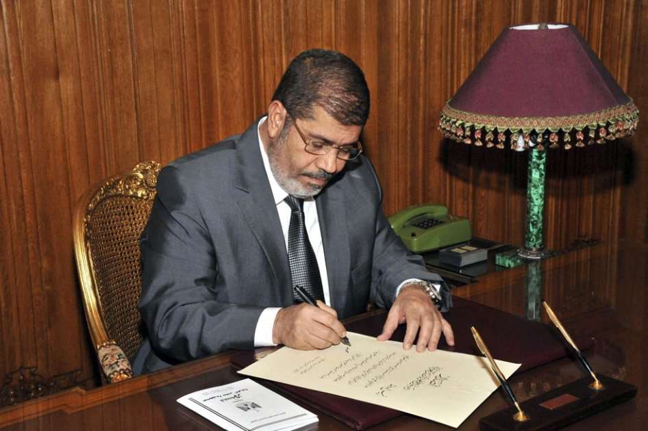 El presidente egipcio Mohamed Mursi firmando el decreto para aprobar la nueva Constitución/ EFE