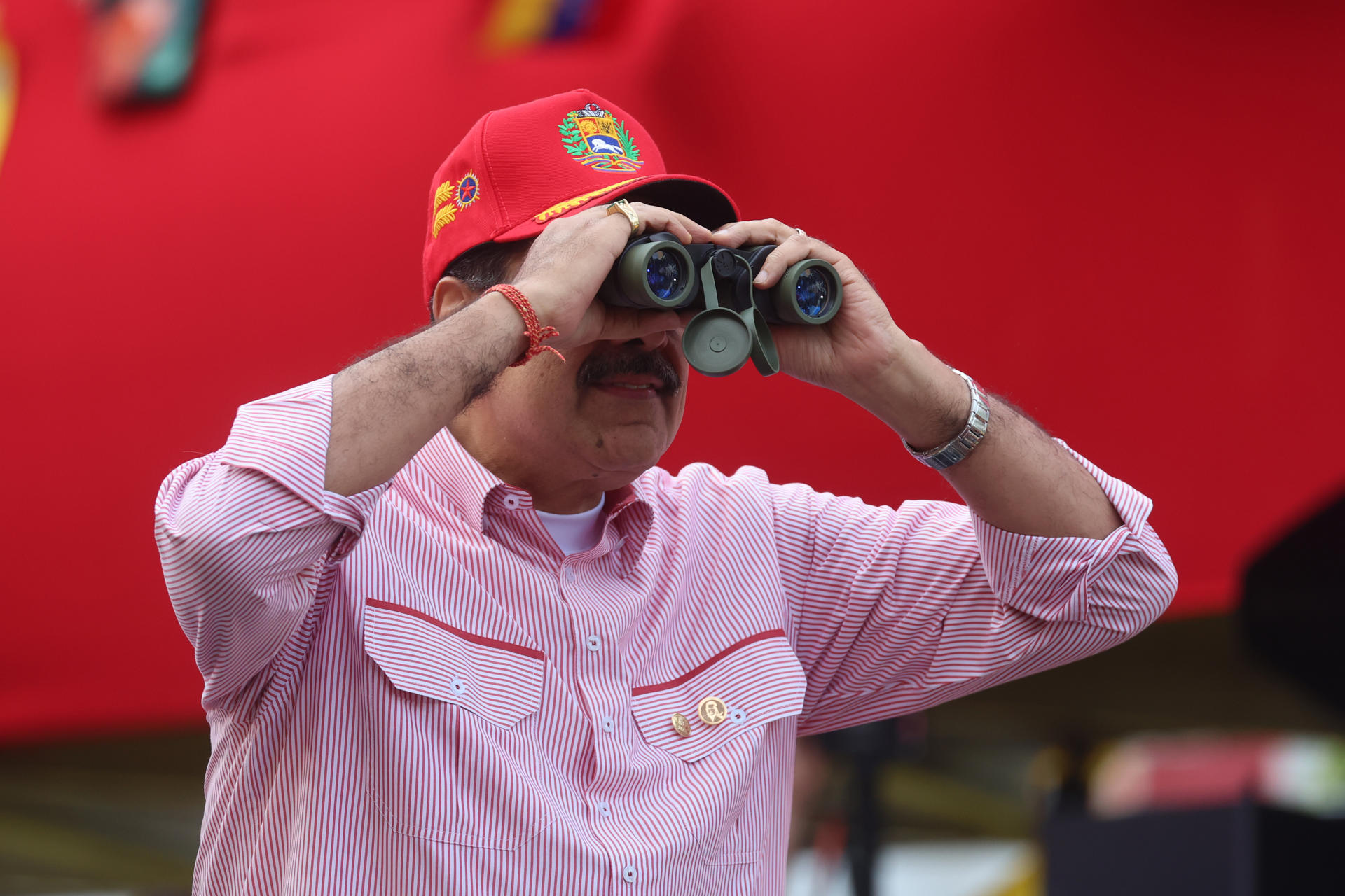 AME4714. CARACAS (VENEZUELA), 01/12/2025.- El presidente de Venezuela, Nicolás Maduro, observa por unos binoculares durante una movilización este lunes, en Caracas (Venezuela). Chavistas afirmaron que buscan la paz, pero están preparados para "defender la patria", durante una movilización para juramentar a los llamados Comandos Bolivarianos Integrales en medio de las tensiones por el despliegue militar de Estados Unidos en el Caribe. EFE/ Miguel Gutiérrez
