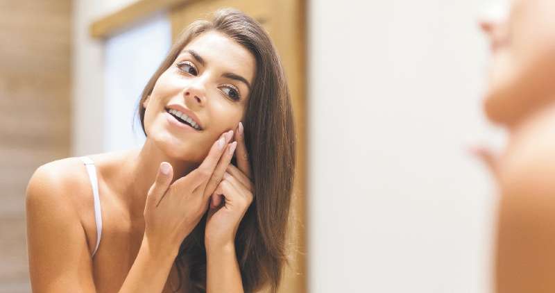 Woman removing pimple from her face