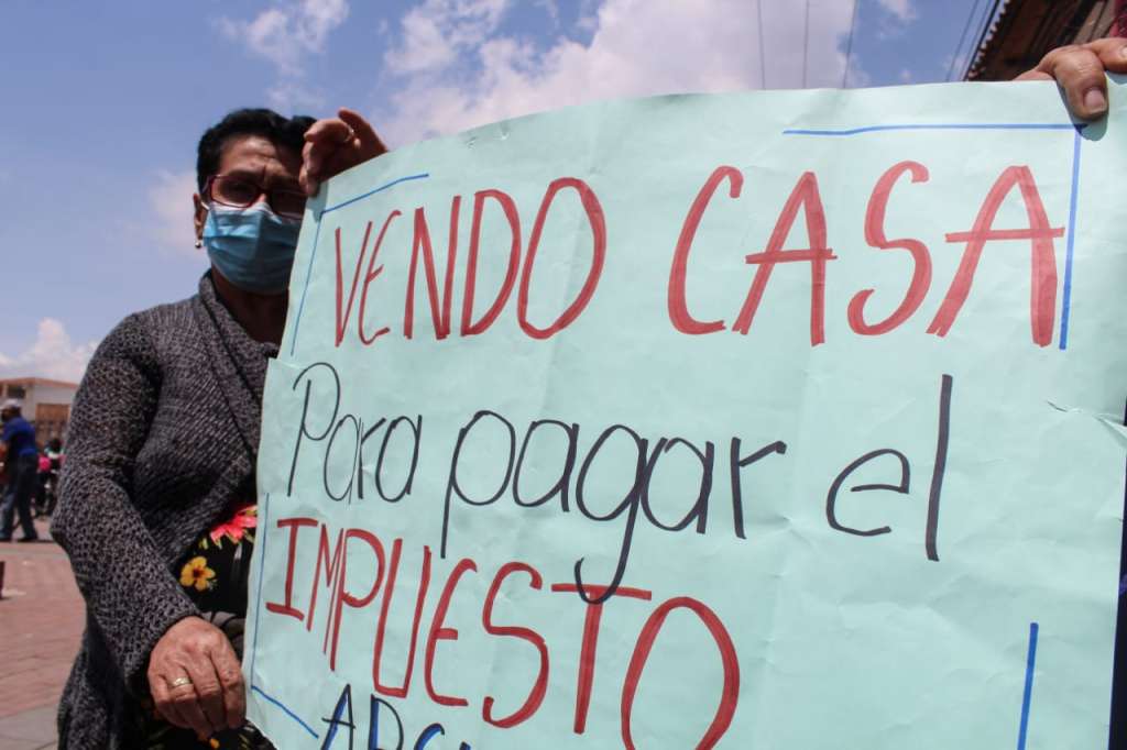 Una mujer sostiene un cartel que dice: vendo mi casa para pagar el impuesto