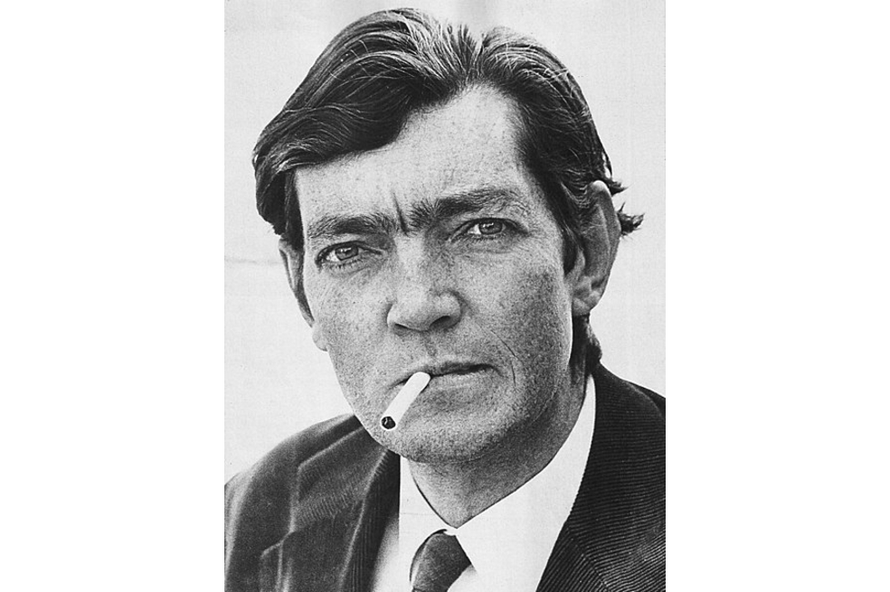 Julio Cortázar está fumando cigarrillo, mientras mira a la cámara.