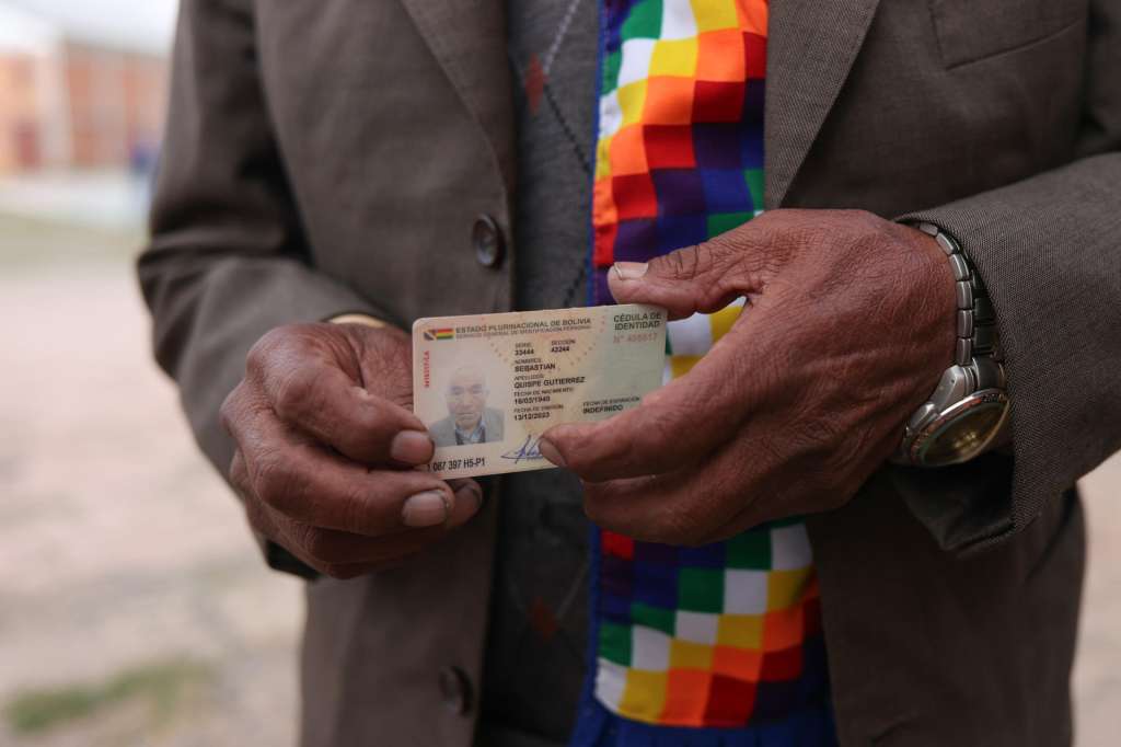 AME9619. LAJA (BOLIVIA), 19/10/2025.- Un hombre sostiene su documento de identificación en un centro votación este domingo, en la comunidad de Laja (Bolivia). Los pobladores de Laja en el altiplano de Bolivia, a 3.800 metros sobre el nivel del mar, acudieron a los colegios electorales cubiertos con frazadas desde temprano y bajo un cielo nublado para votar en la inédita segunda presidencial del país con la esperanza de que la crisis económica termine con el próximo gobierno. EFE/ Luis Gandarillas
