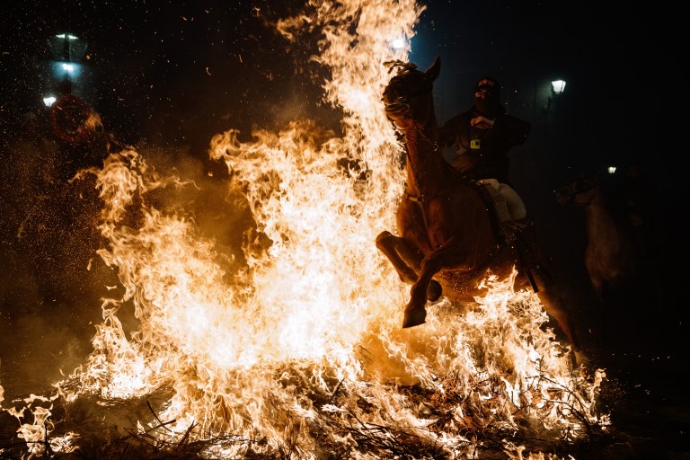 FOTOGALERÍA 6 DE 10.- SAN BARTOLOMÉ DE PINARES (ÁVILA), 16/01/2023.- Un jinete pasa con su caballo por encima de las llamas durante las tradicionales "luminarias" que se celebran hoy lunes en la localidad abulense de San Bartolomé de Pinares. EFE / Raúl Sanchidrián.