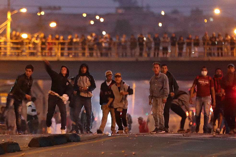 Un grupo de manifestantes enfrenta policías antimotines que protegen el supermercado Merkandrea. / Agencia EFE