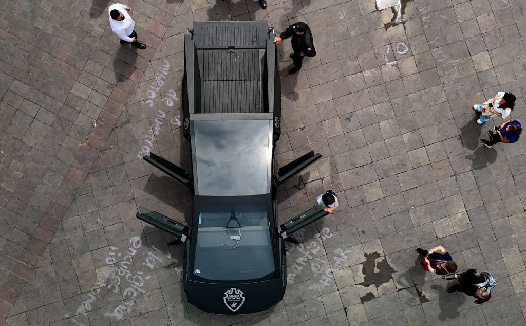 This aerial view shows locals looking at a state police Tesla Cybertruck, a vehicle equipped with specialized technology for public safety which is being used as a patrol car within a new security strategy, in Guadalajara, Jalisco state, Mexico, on May 29, 2025. (Photo by STRINGER / AFP)