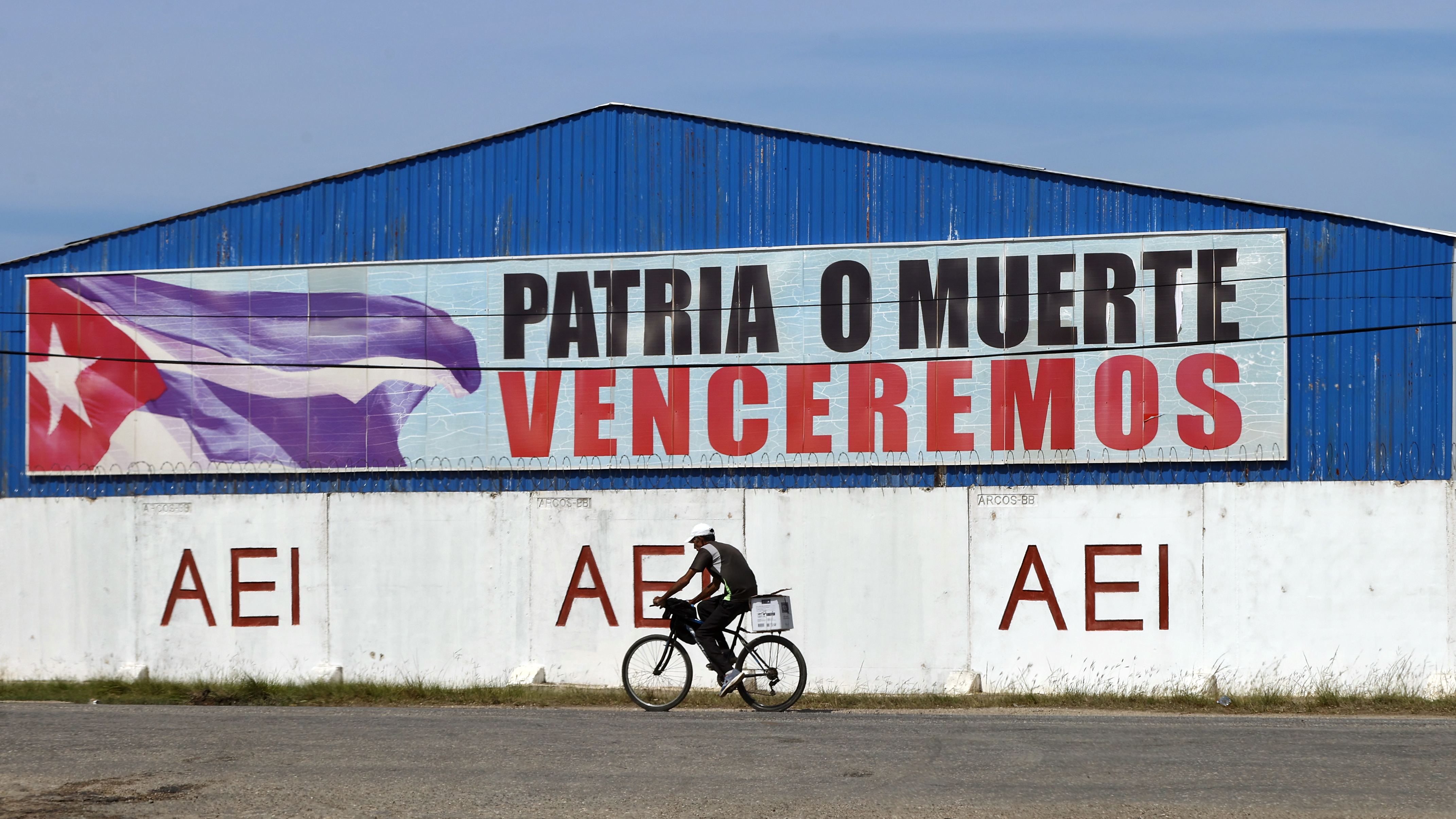 AME5469. CÁRDENAS (CUBA), 04/04/2025.- Una persona pasa en bicicleta frente a un cartel con la consigna 'Patria o Muerte Venceremos' este viernes en la ciudad de Cárdenas al este de La Habana (Cuba). EFE/Ernesto Mastrascusa