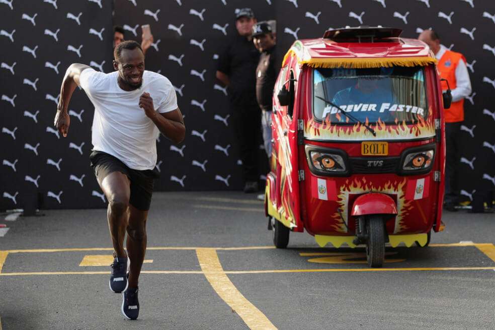 Usain Bolt en una competencia ante un vehículo en Lima, Perú. / EFE