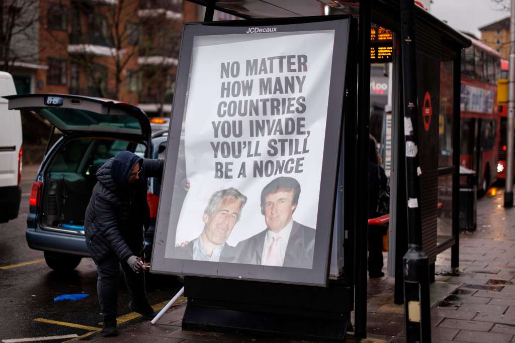 LONDON (United Kingdom), 09/01/2026.- A worker removes a poster placed at a bus stop by British political campaign group 'Everyone Hates Elon' featuring a picture of US President Donald J. Trump and convicted sex offender Jeffrey Epstein reading 'No matter how many countries you invade, you'll still be a nonce', near the US Embassy in London, Britain, 09 January 2026. (Protestas, Reino Unido, Londres) EFE/EPA/TOLGA AKMEN