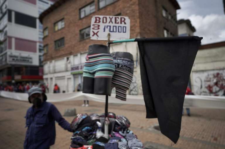Un hombre al lado de dos maniquies de los que cuelgan boxer para hombre.