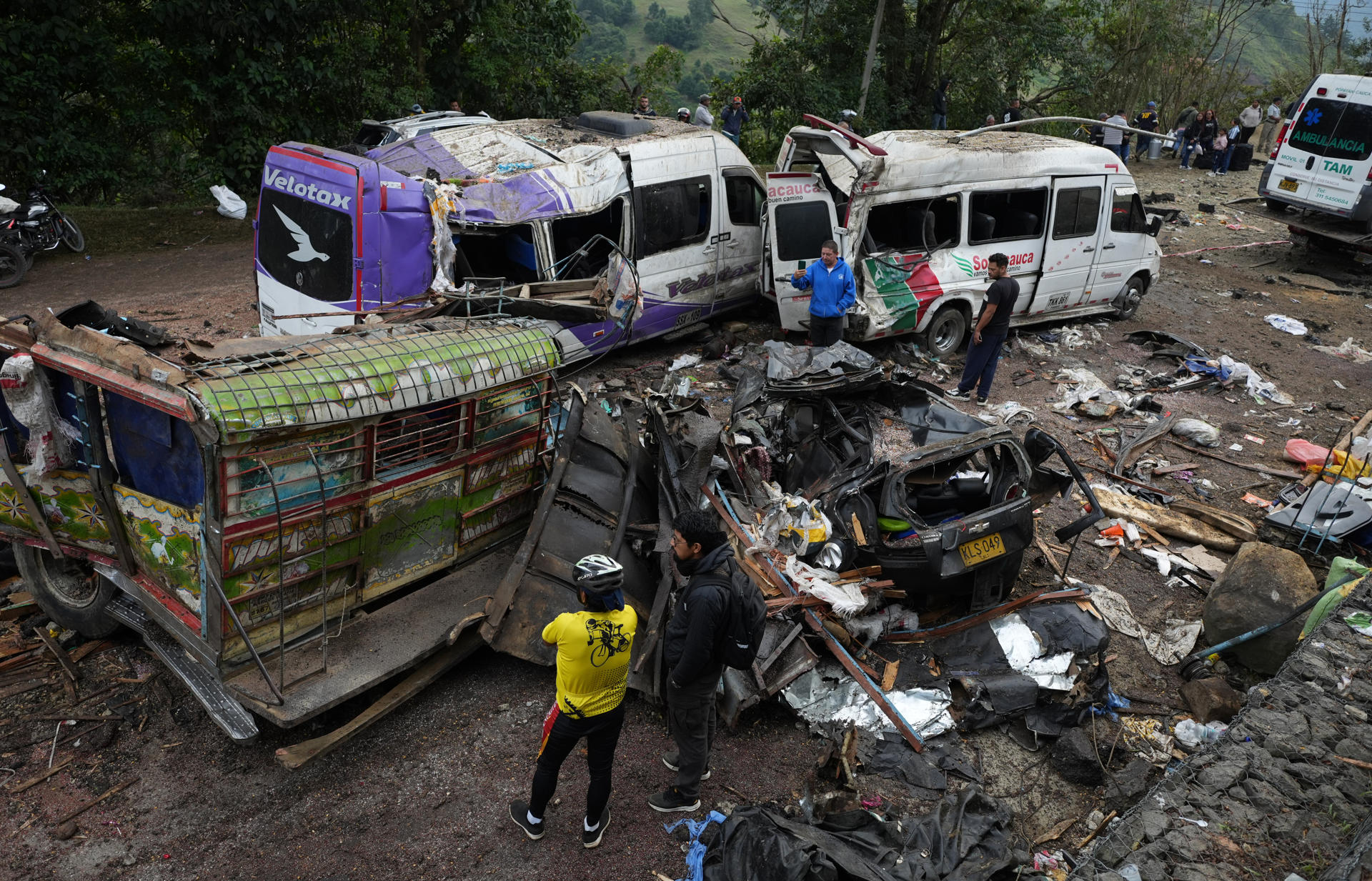 AME6842. CAJIBÍO (COLOMBIA), 26/04/2026.- Personas observan este domingo vehículos destruidos por un atentado ocurrido en la Vía Panamericana en Cajibío (Colombia). El número de personas muertas por el ataque guerrillero de este sábado con un cilindro bomba en la Vía Panamericana, en el suroeste de Colombia, subió a 14, todos civiles, y el de heridos a 38, informó el gobernador del departamento del Cauca, Octavio Guzmán. EFE/Ernesto Guzmán