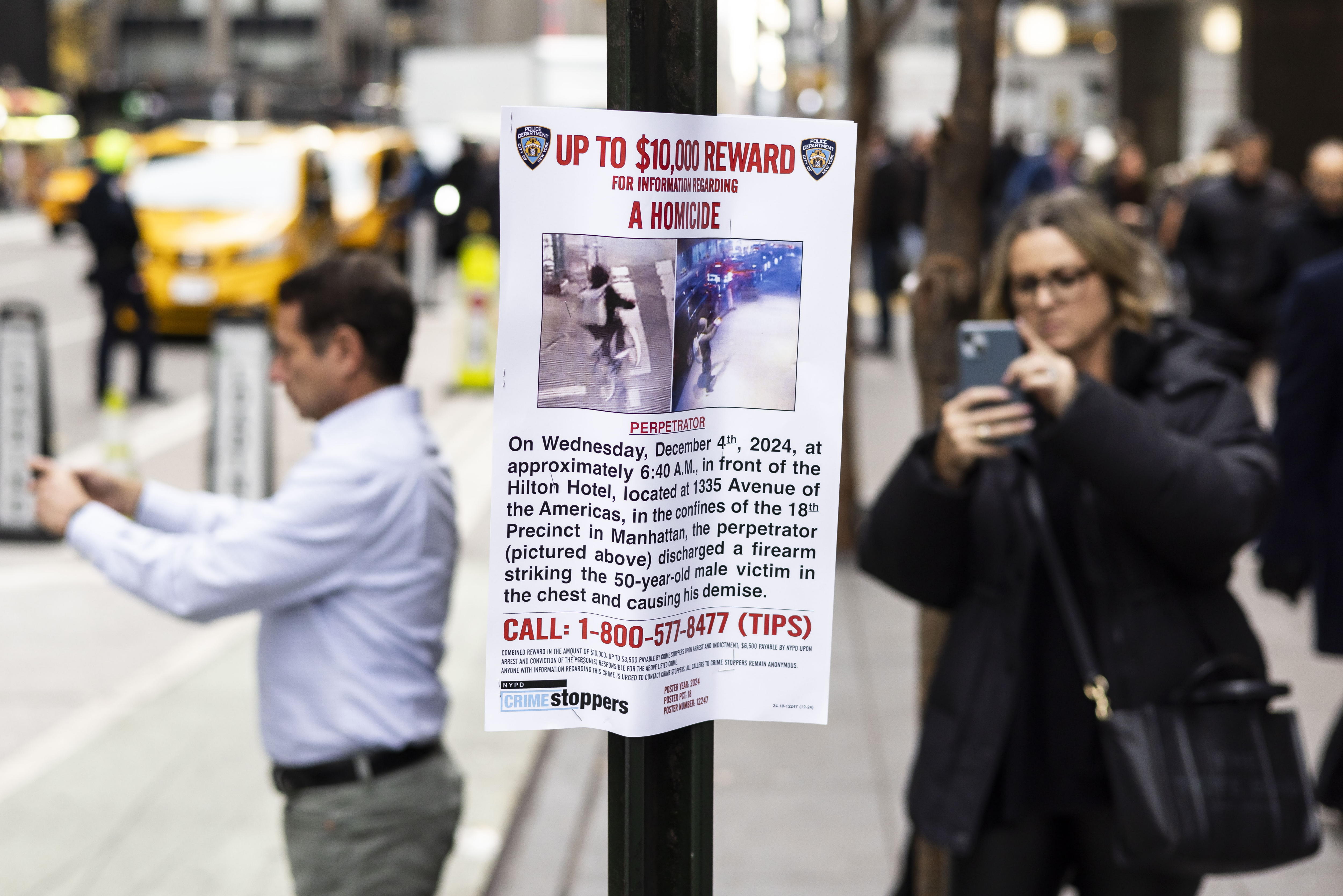 New York (United States), 04/12/2024.- People look at a 'Wanted' poster put up by the New York City police department outside of the New York Hilton hotel near the scene where UnitedHealthcare'Äôs CEO Brian Thompson was shot and killed in an apparent targeted attack as he was en-route to attend UnitedHealthcare'Äôs annual investor conference this morning in New York, New York, USA, 04 December 2024. The masked gunman is still being sought following the early morning shooting in Manhattan after fleeing towards Central Park. (Nueva York) EFE/EPA/JUSTIN LANE