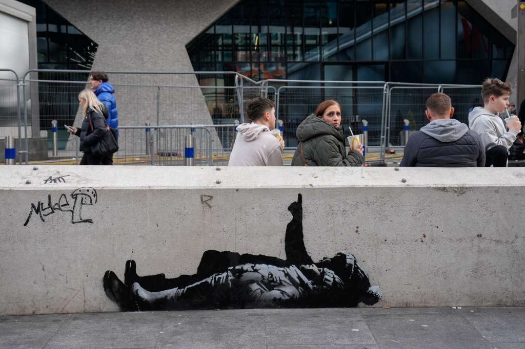 Los peatones pasan junto a al mural creado por el artista callejero Banksy, en una zona de Tottenham, Court Road, en el centro de Londres.