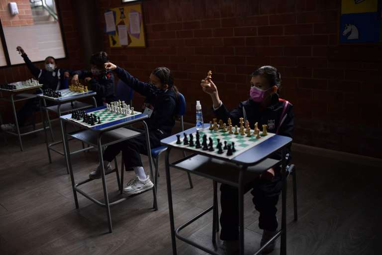 Niños con tapabocas jugando ajedrez.