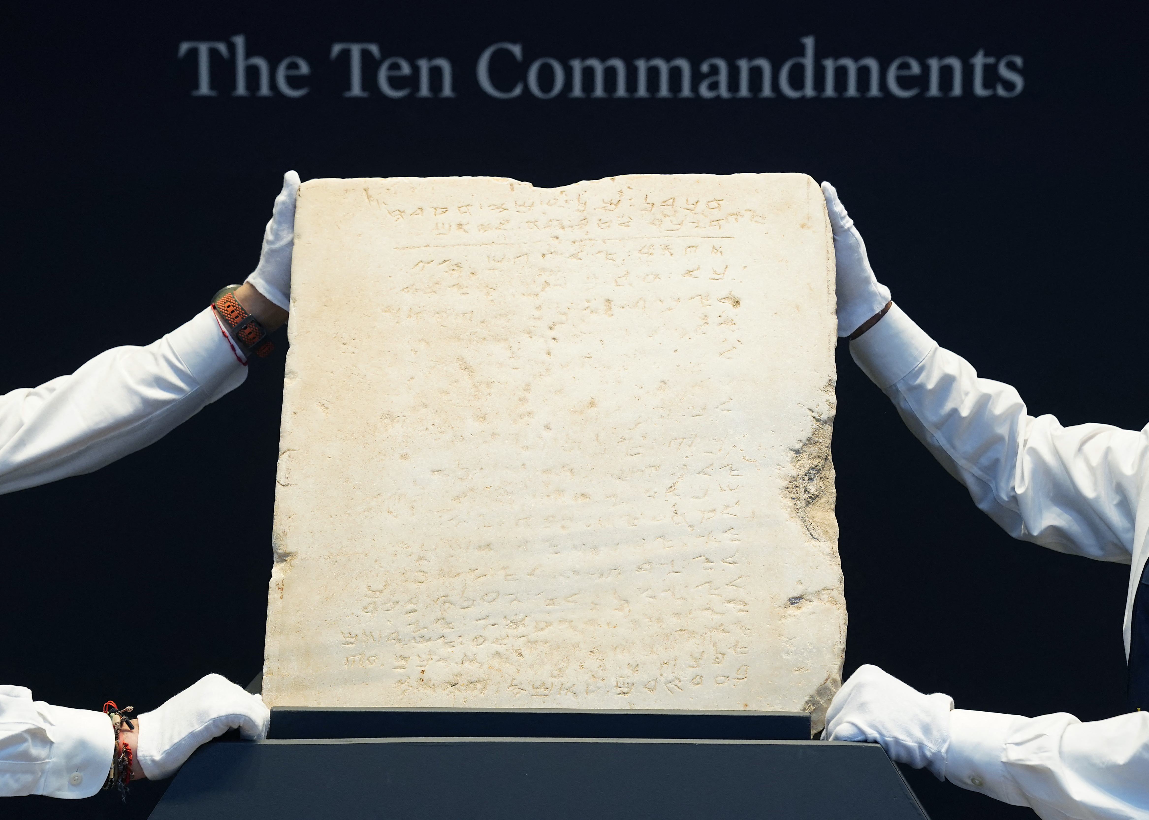 Sotheby’s workers hold one of the most widely known and influential texts in history: the oldest inscribed stone tablet of the Ten Commandments during a press preview at Sotheby’s in New York, on December 9, 2024.