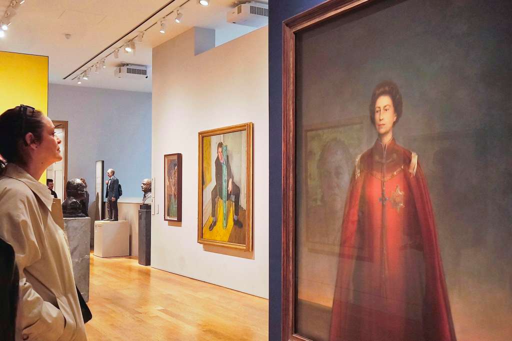 LONDRES, 21/04/2026.- Una mujer contempla un retrato de la reina Isabel II en la National Portrait Gallery de Londres. Este martes, se cumplen cien años del nacimiento de Isabel II, la reina que marcó la época contemporánea del Reino Unido, con siete décadas portando la corona, un tiempo en el que vio a su país perder todo un imperio, ingresar y luego salir de la Unión Europea, y que mantuvo un prestigio intacto pese a los escándalos que rodearon a buena parte de la familia real. EFE/ Guillermo Garrido
