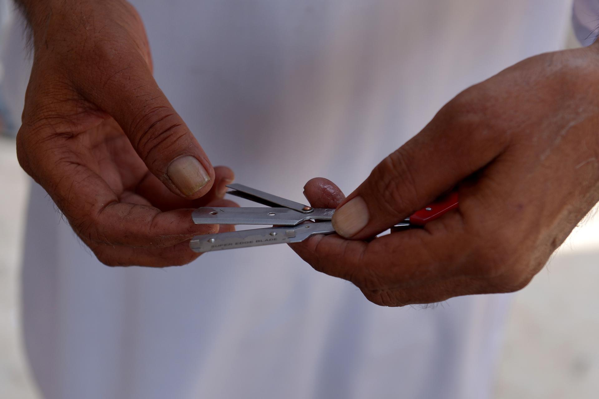 PESHAWAR (Pakistan), 28/07/2025.- A barber changes razor blades at a roadside shop, as the world observes International Hepatitis Day, in Peshawar, Pakistan, 28 July 2025. According to doctors, pricking in a drip bottle, reuse of syringes, blood transfusion, ear-nose piercing equipment, and the reuse of razor blades at barber shops are the main causes of Hepatitis spread. The 2025 World Hepatitis Day theme is 'Hepatitis: Let's Break It Down'. EFE/EPA/BILAWAL ARBAB