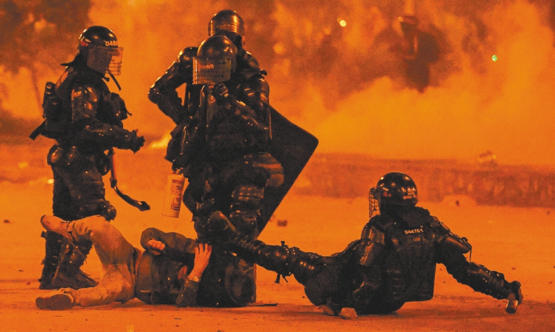 TOPSHOT - Riot police detain a demonstrator during a protest against the government of Colombian President Ivan Duque in Bogota on June 12, 2021. Dozens of people have been killed in protests that erupted around the country on April 28, initially against a tax hike that would have mostly affected the middle classes, but which have morphed into a major anti-government movement. / AFP / Juan BARRETO