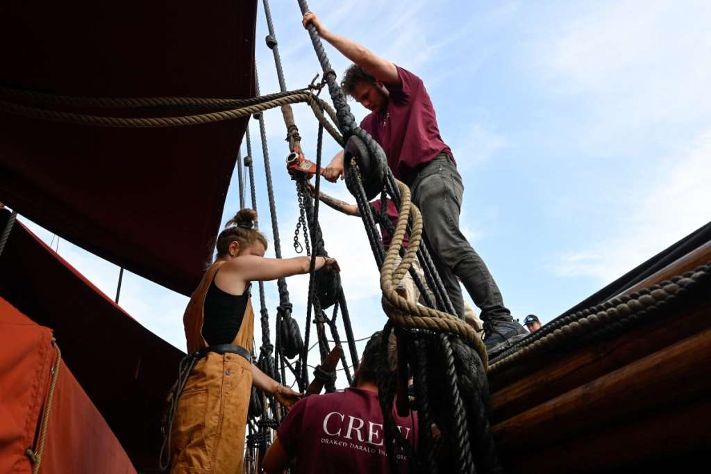 Crew members of the Draken Harald Harfagre (the ship used in the movie the Odyssey) work on board as the ship is docked outside Oslo Opera in the Norwegian capital on August 14, 2026. Ulysses on a Viking ship? Two millennia separate the two worlds. Yet it�s precisely on board such a vessel that Christopher Nolan has the Greek hero sail in �The Odyssey,� a deliberate anachronism in the service of realism. With its tar-soaked ropes, creaking oak deck, and fifty slender spruce oars, the Draken Harald H�rfagre, the largest modern replica of a Viking ship, has, for the duration of a film shoot, swapped the fantasy of Scandinavian sagas for that of Greek mythology. (Photo by Jonathan KLEIN / AFP)
