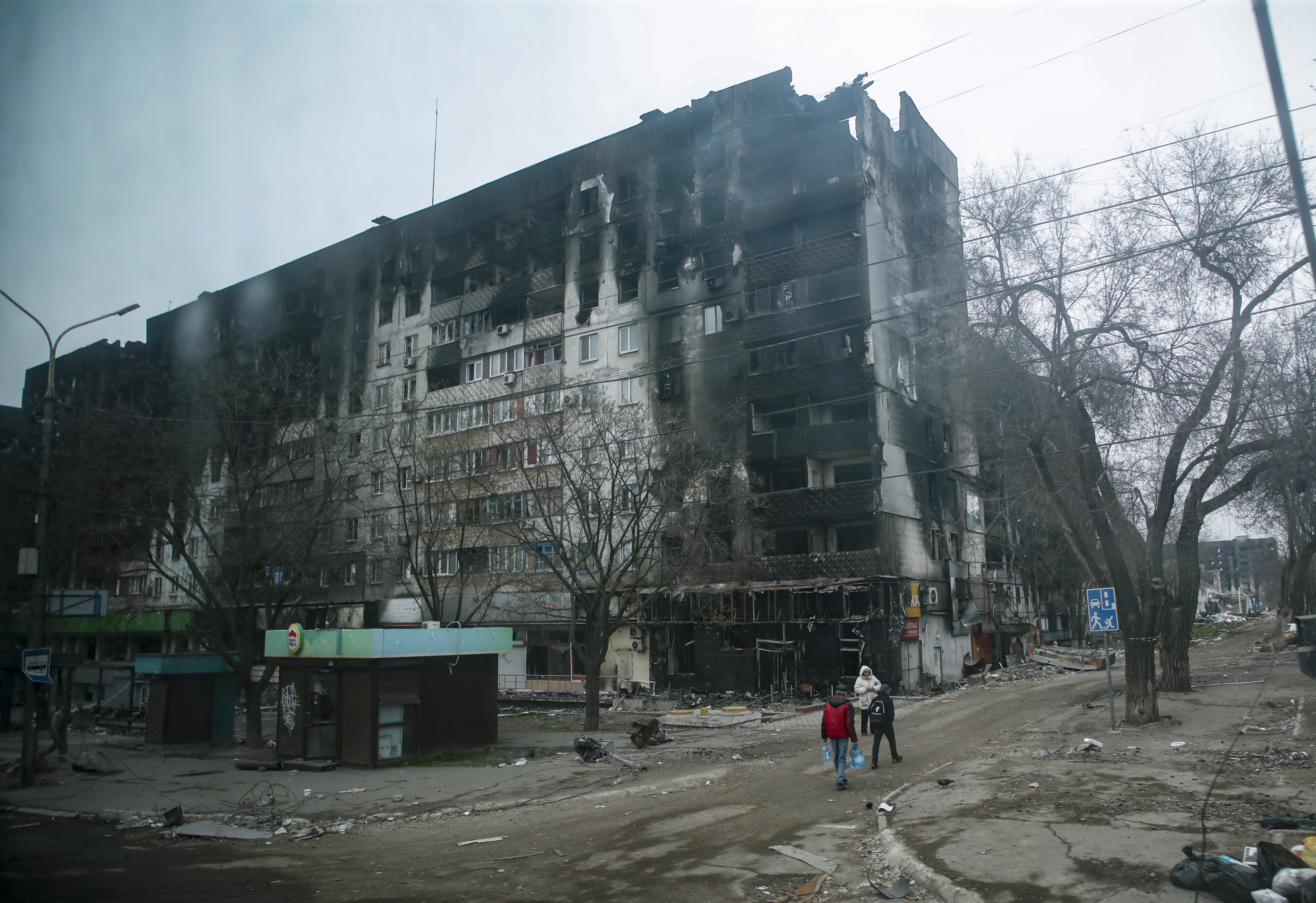 Mariupol (Ukraine), 12/04/2022.- A picture taken during a visit to Mariupol organized by the Russian military shows local people cary water near devesteted and burned apartment building in downtown Mariupol, Ukraine, 12 April 2022. For more than a month, hostilities have continued in the city. There is no water, electricity, gas or communications. Shops, pharmacies and hospitals are closed. 250 thousand inhabitants left the city, about 300 thousand still remain. During the hostilities, up to 70 percent of the housing stock of Mariupol was destroyed and five thousand residents of the city was killed said the new mayor of the city Konstantin Ivashchenko. On 24 February Russian troops had entered Ukrainian territory in what the Russian president declared a 'special military operation', resulting in fighting and destruction in the country, a huge flow of refugees, and multiple sanctions against Russia. (Rusia, Ucrania, Estados Unidos) EFE/EPA/SERGEI ILNITSKY