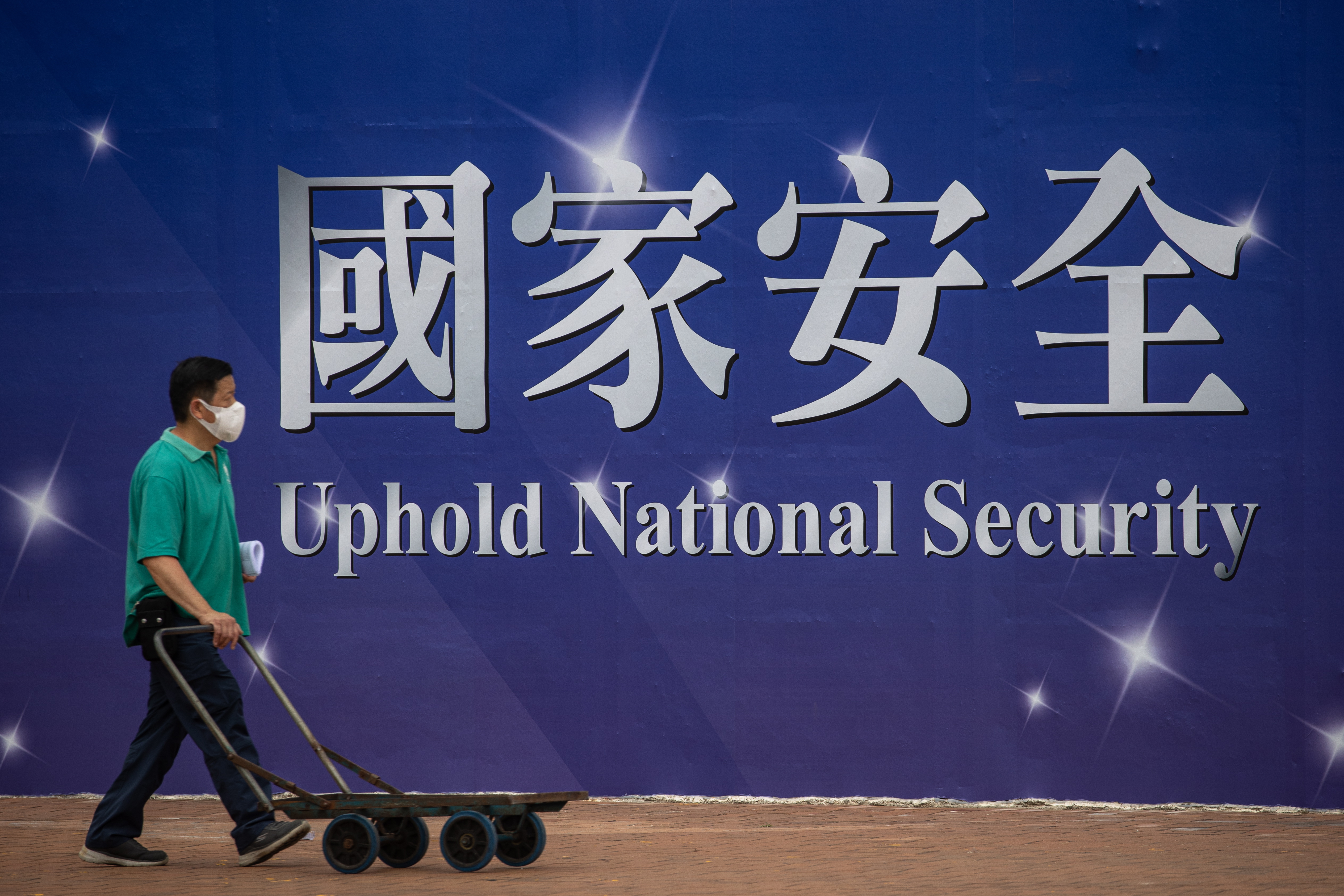 Hong Kong (China), 13/04/2022.- A man pushes a trolley past a banner promoting the national security law in Hong Kong, China, 13 April 2022. The election for Chief Executive will take place in Hong Kong next month. (Elecciones) EFE/EPA/JEROME FAVRE
