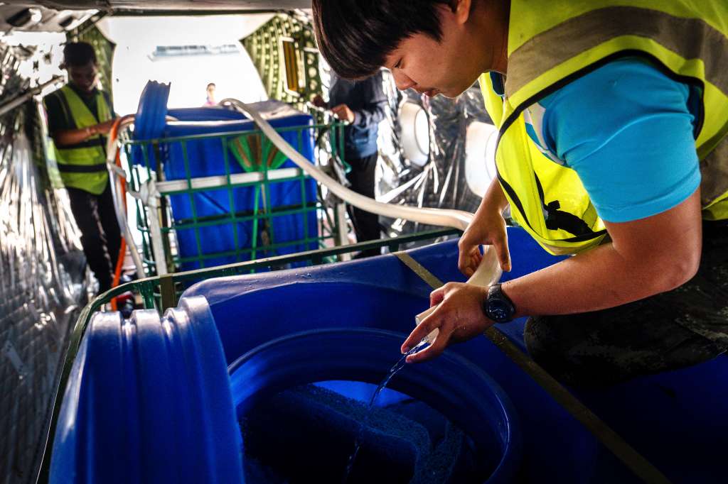 CORRECTION / This photo taken on January 15, 2025 shows a worker with Thailand's Royal Rainmaking department adding water and ice to a container to spray in the air as part of an atmospheric modification mission to displace pollution, at an airport in Hua Hin in Prachuap Khiri Khan province.