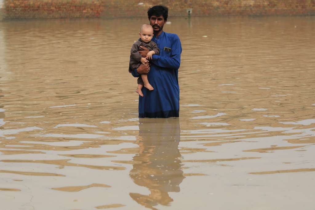 Charsadda (Pakistan), 27/08/2022.- A man holding a baby wades through a flooded area following heavy rains in Charsadda District, Khyber Pakhtunkhwa province, Pakistan, 27 August 2022. According to the National Disaster Management Authority (NDMA) on 26 August, flash floods triggered by heavy monsoon rains have killed over 900 people across Pakistan since mid-June 2022. More than 33 million people have been affected by floods, the country's climate change minister said. (Inundaciones) EFE/EPA/ARSHAD ARBAB