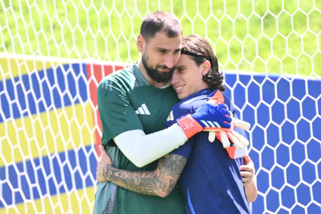 TOPSHOT - Italy's goalkeeper #01 Gianluigi Donnarumma embraces Italy's defender #05 Riccardo Calafiori during an MD-1 training session at the base camp in Iserlohn on June 28, 2024, on the eve of their UEFA Euro 2024 Round of 16 football match against Switzerland.