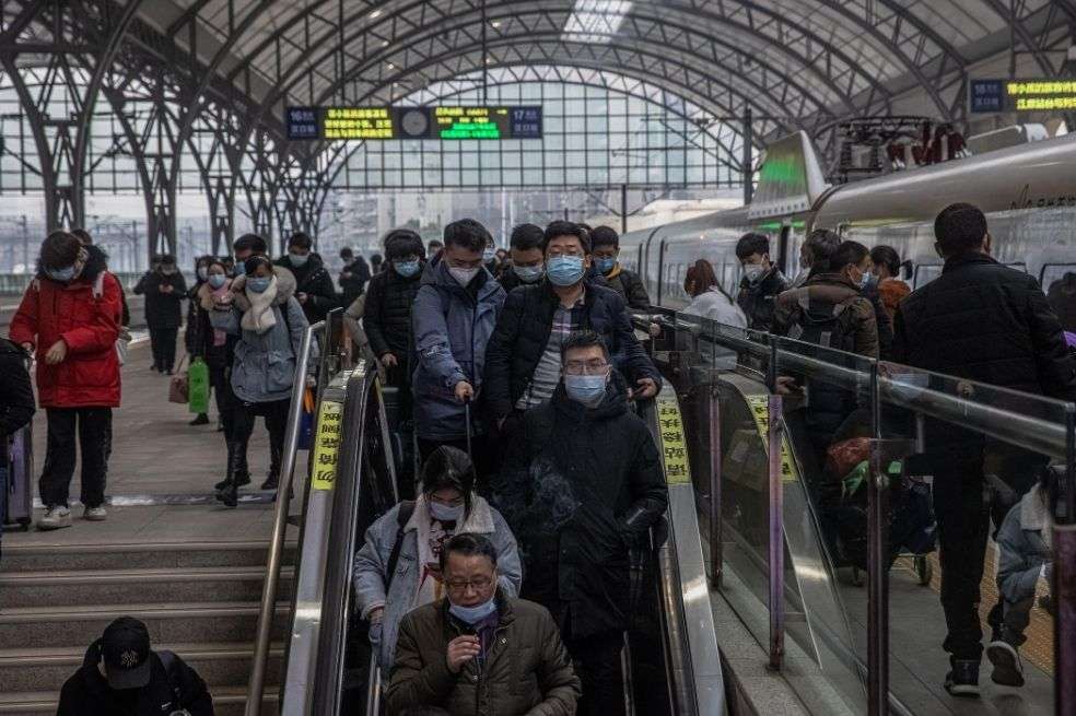 Pasajeros con mascarillas protectoras y su equipaje en la estación de tren de Hankou, en Wuhan (China).