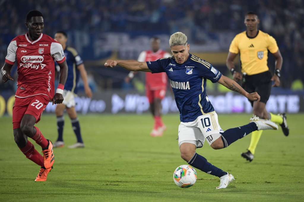 Daniel Cataño, de Millonarios, conduce la pelota ante la marca de Yílmar Velázquez.