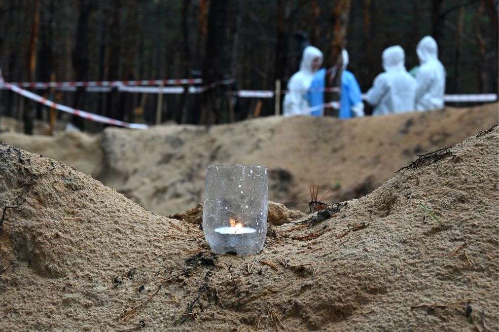 Una vela arde junto a una tumba desenterrada en un bosque cerca de Izyum, en el este de Ucrania.