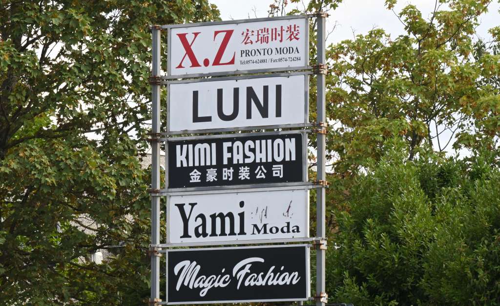 This photograph show advertising signs for fast-fashion outlet factories in the industrial district of Prato, central Italy, on August 1, 2025.