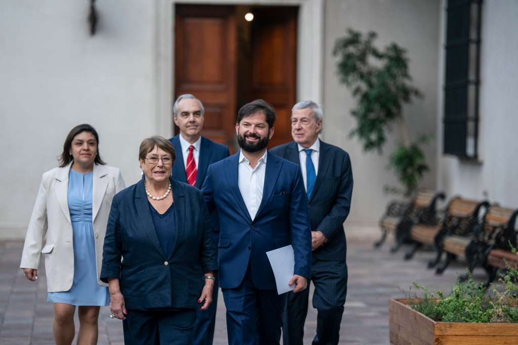 AME1077. SANTIAGO (CHILE), 02/02/2026.- Fotografía cedida por la Presidencia de Chile del mandatario Gabriel Boric (c), junto a la expresidenta Michelle Bachelet (2i) caminando este lunes, en el palacio de La Moneda, en Santiago (Chile). Boric, anunció este lunes la inscripción formal de la candidatura de la expresidenta Michelle Bachelet (2006-2010 y 2014-2018) en las elecciones de finales de año para ocupar la Secretaría General de las Naciones Unidas. EFE/EFE/ Presidencia De Chile /SOLO USO EDITORIAL/SOLO DISPONIBLE PARA ILUSTRAR LA NOTICIA QUE ACOMPAÑA (CRÉDITO OBLIGATORIO)