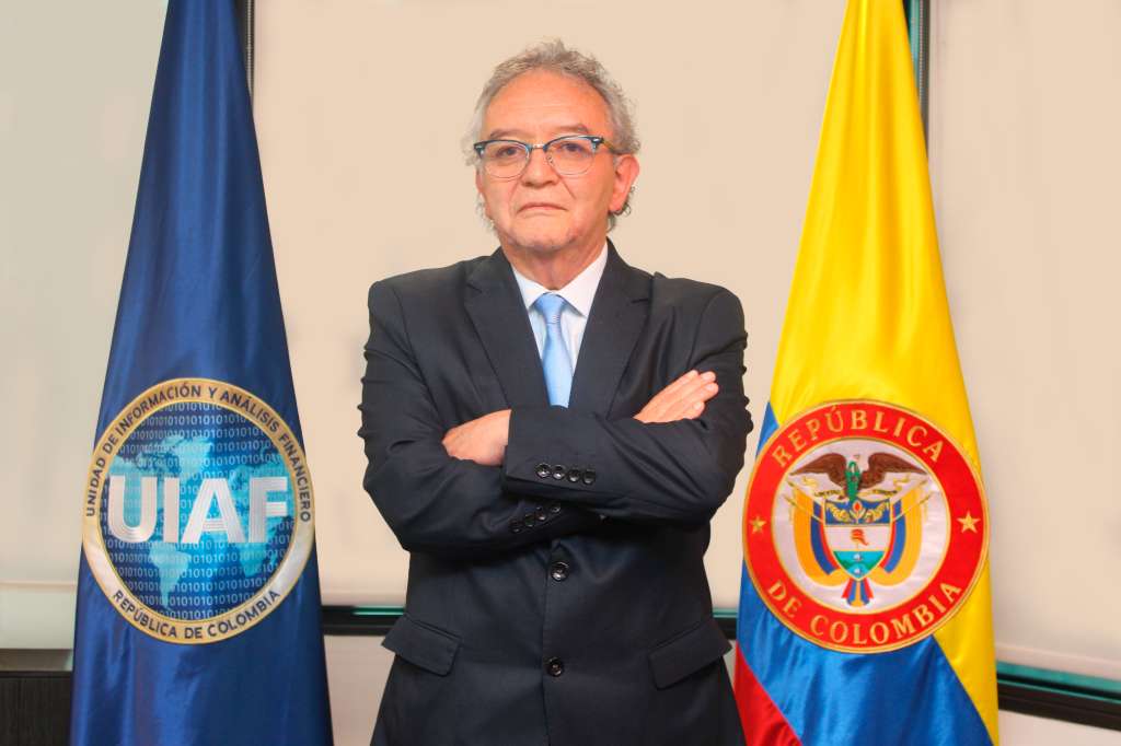 Jorge Arturo Lemus, de pie, en plano medio, entre la bandera de la UIAF y la de Colombia.
